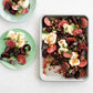 Roasted beets and cauliflower on a baking tray with two green plates of the same dish.