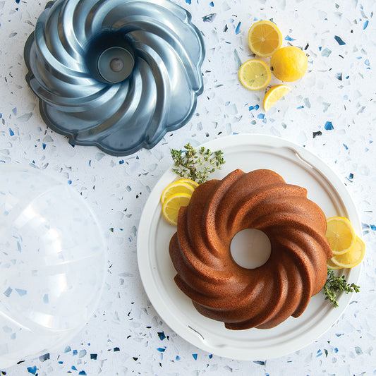 Bundt cake with lemon slices and a bundt pan on a speckled countertop