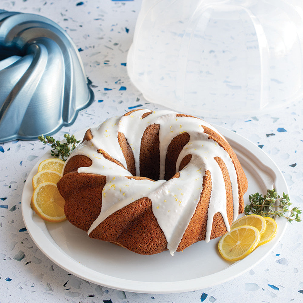 Bundt cake with lemon slices and thyme on a white plate
