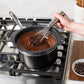 Person stirring chocolate in a pot on a stove with a whisk