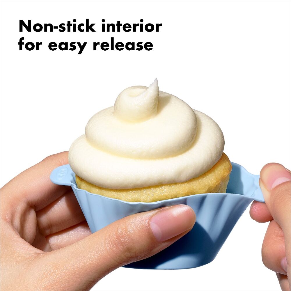 Person holding a cupcake with a blue silicone liner, text 'Non-stick interior for easy release' above.