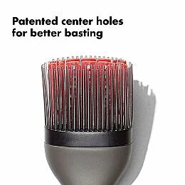 Barbecue brush with red bristle tips on a white background, highlighting patented center holes.