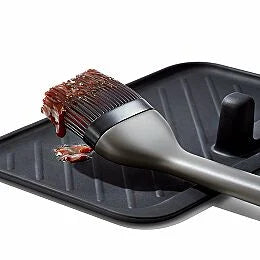 Basting brush with brown sauce on a black tray