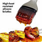 Barbecue brush with high-heat resistant silicone bristles applying sauce to grilled vegetables on a white background.