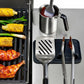 Grilling scene with corn, chicken, and cooking utensils on a metal surface.