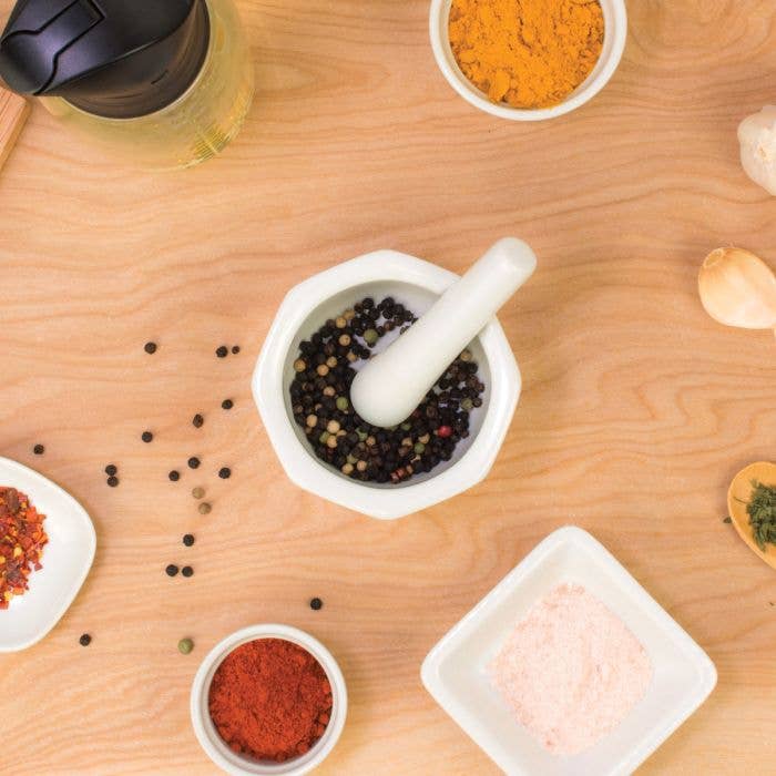 Mortar and pestle with herbs and spices on a wood surface