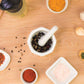 Mortar and pestle with herbs and spices on a wood surface