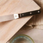 Knife with a black handle on a wooden cutting board