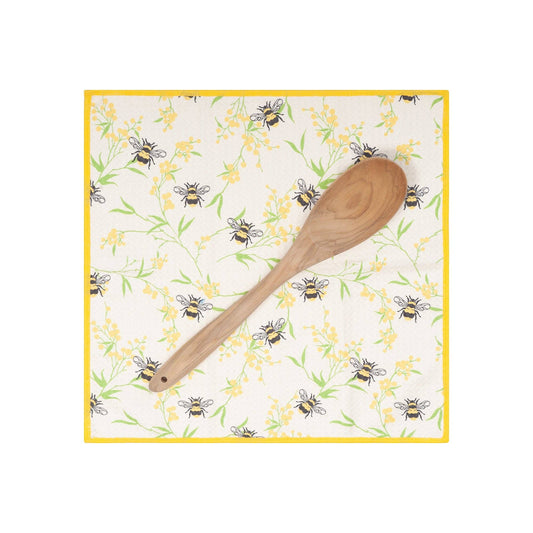 Wooden spoon on a decorative cloth with bee and flower pattern