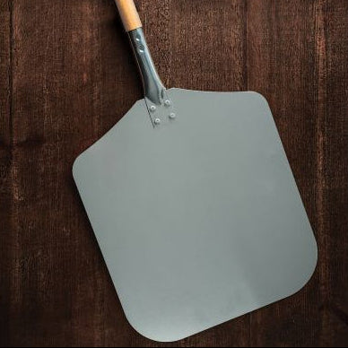 Gray pizza peel with wooden handle on a wooden background