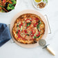 Pizza with red peppers and spinach on a white surface with a pizza cutter.
