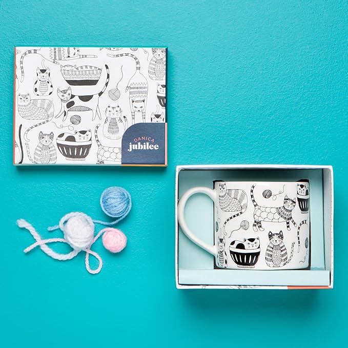 Mug in a Box - Purr Party from Danica Jubilee! This enchanting set features a delightful ceramic mug, adorned with whimsical cat designs that are sure to bring a smile to any feline lover's face. Each 14-ounce stoneware mug comes beautifully packaged in a gift-ready box