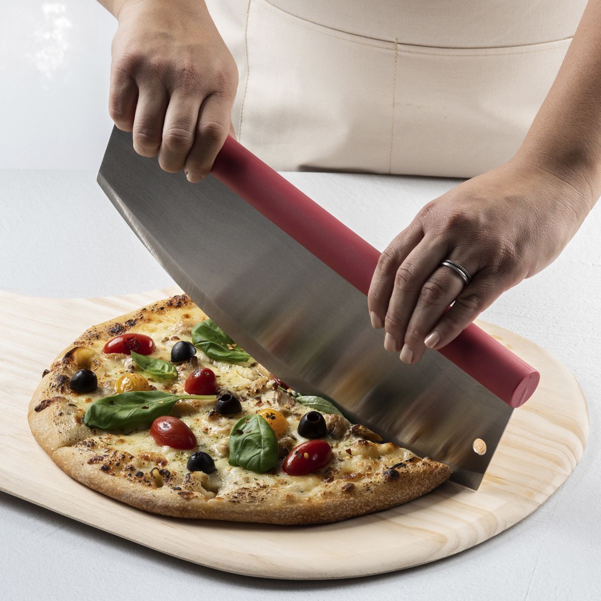 Rocking Pizza Cutter with Blade Guard being used to cut a pizza on a cutting board. 