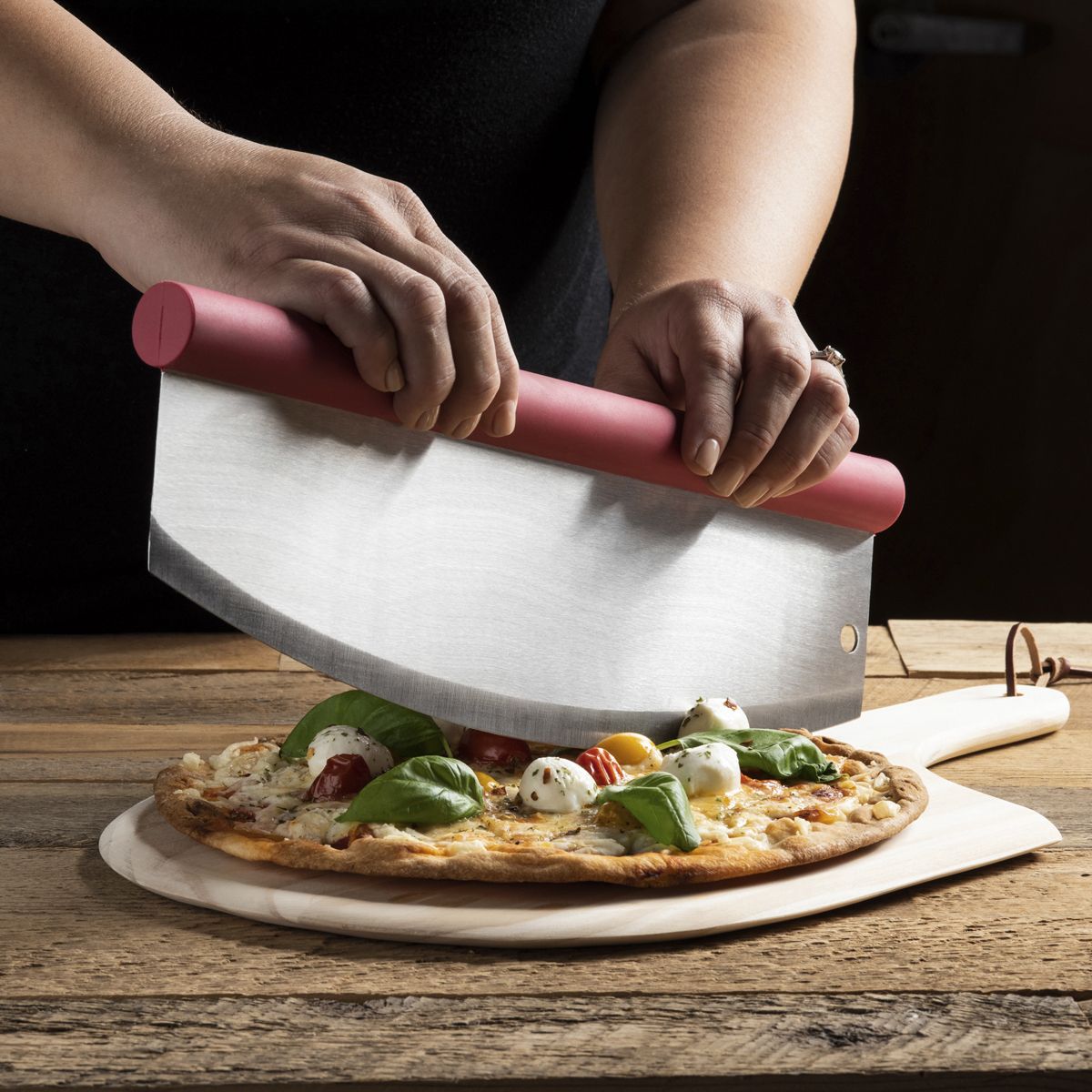 Rocking Pizza Cutter with Blade Guard being used to cut a pizza on a pizza peel. 
