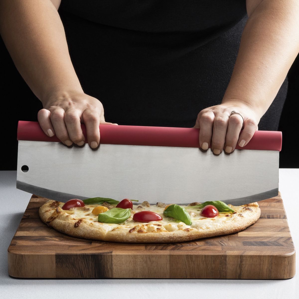 Rocking Pizza Cutter with Blade Guard being used to cut a pizza on a dark wood cutting board. 