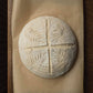 Round loaf of bread with cross-cut pattern on a textured surface