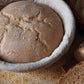 Loaf of bread in a white ceramic dish on a patterned surface