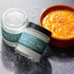 Two jars of Saltwerk Flaky Sea Salt on a metallic surface with a bowl of caviar.