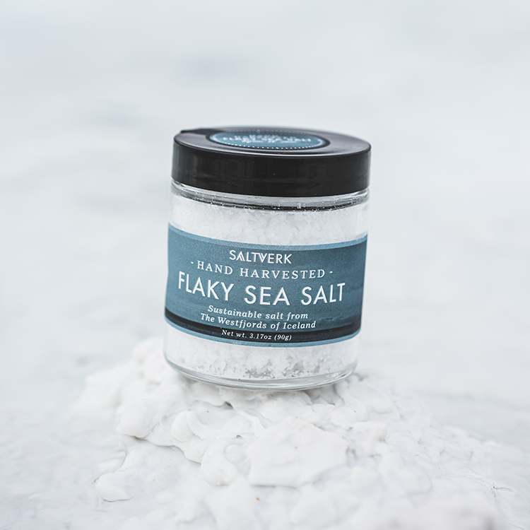 Jar of flaky sea salt with a label on a white background