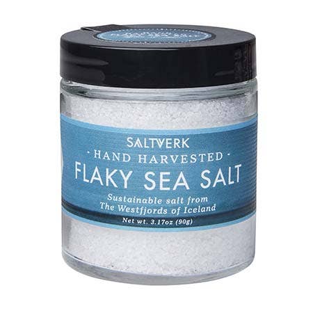 Jar of flaky sea salt with a blue label on a white background