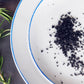White plate with black crumbly salt on a dark surface