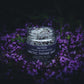 Jar of Saltwerk Arctic Thyme Salt surrounded by purple flowers on a dark background
