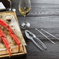 Seafood cracker and picks on a black surface with crab legs and a cutting board