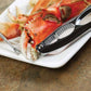 Seafood Crackerand pick on a white plate with a crab letg on a brown surface