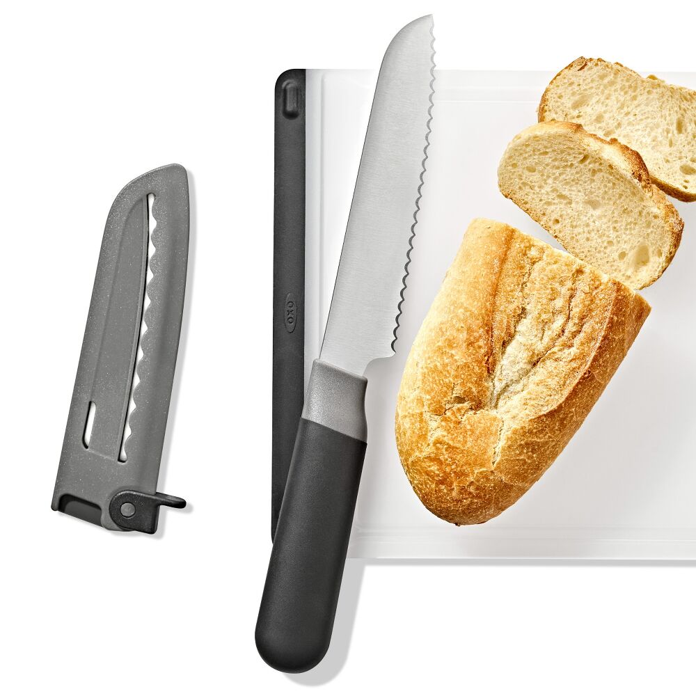 Serrated knife on a white cutting board with a loaf of bread