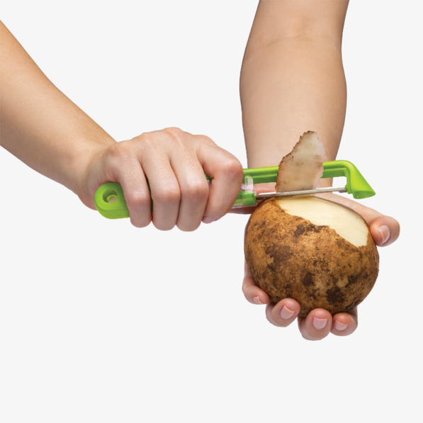 Person using a green potato peeler on a potato.