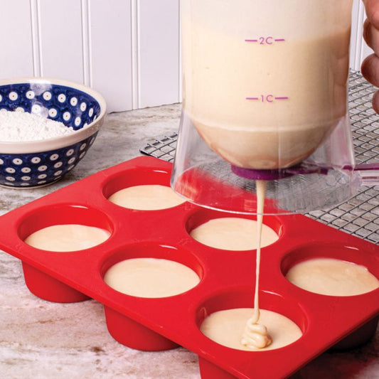 Silicone mold with batter being poured into it on a kitchen counter.