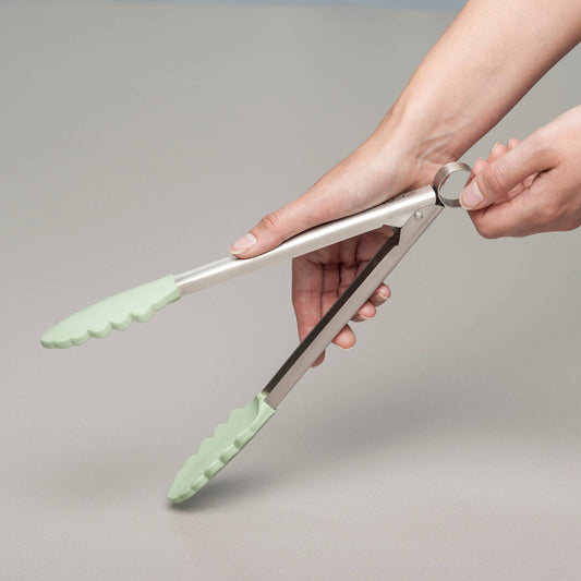 Grip, flip, and serve with ease using the Silicone Tongs in Coastal Green! Featuring scalloped, non-scratch silicone tips, these premium kitchen tongs provide the perfect hold for everything from delicate greens to sizzling steaks. The brushed stainless steel handle offers durability, while the smart locking mechanism keeps them neatly stored when not in use. 