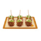 Four caramel apples on a wooden board with a white background