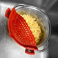 Red silicone strainer over a pot of cooked pasta in a sink.