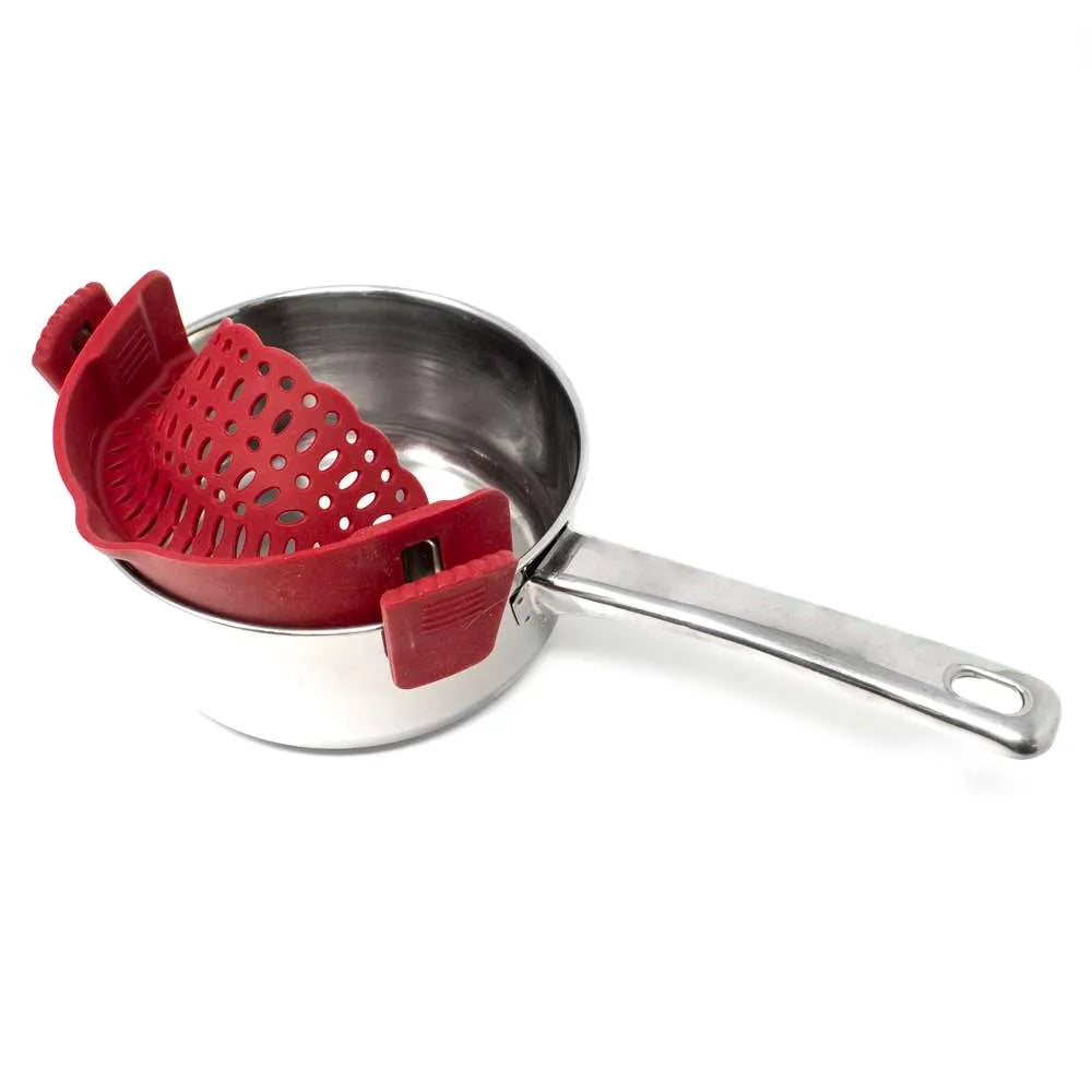 A stainless steel saucepan with a red silicone strainer insert resting inside it, shown on a clean white background.