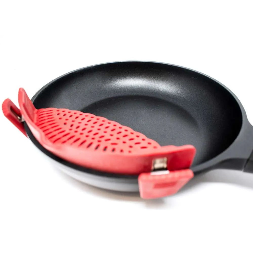 A red silicone pan lifter and handle cover attached to a black frying pan on a white background.