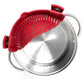 Red silicone strainer basket with side clips, shown resting over the rim of a stainless steel pot on a white background.
