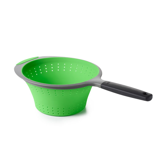 Green colander with a black handle on a white background