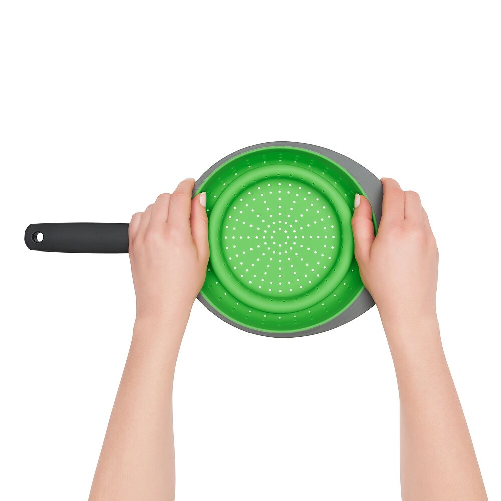 hands collapsing a silicone strainer onto a white surface. 