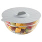 Glass bowl with a gray lid filled with fruits on a white background