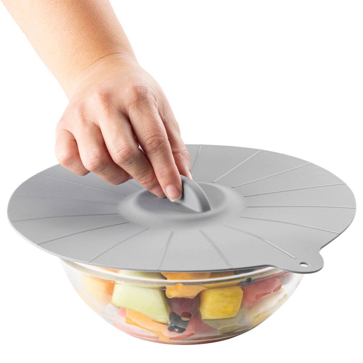 Gray silicone lid being placed on a bowl of fruit by a hand.