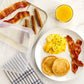 Breakfast setting with pancakes, eggs, bacon, and sausages on a white plate, with a side of orange juice.