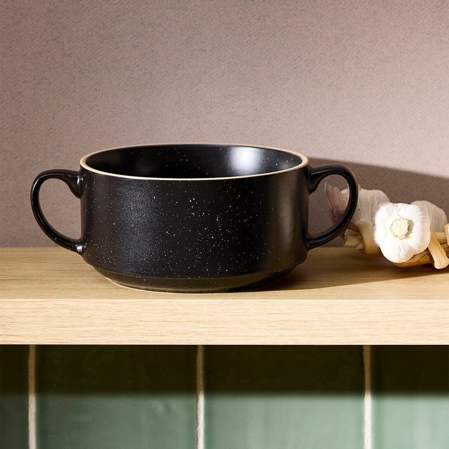 Black ceramic bowl on a wooden surface with a neutral background