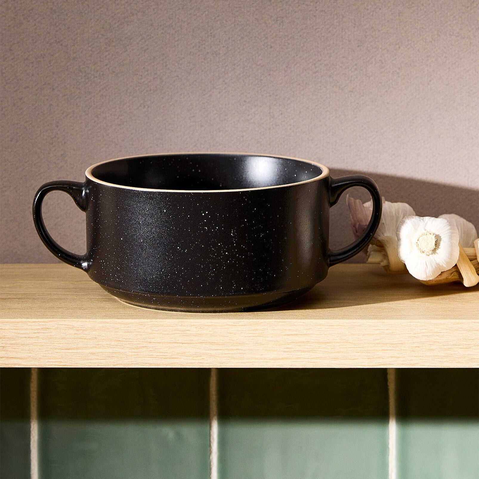 Black ceramic bowl on a wooden surface with a neutral background