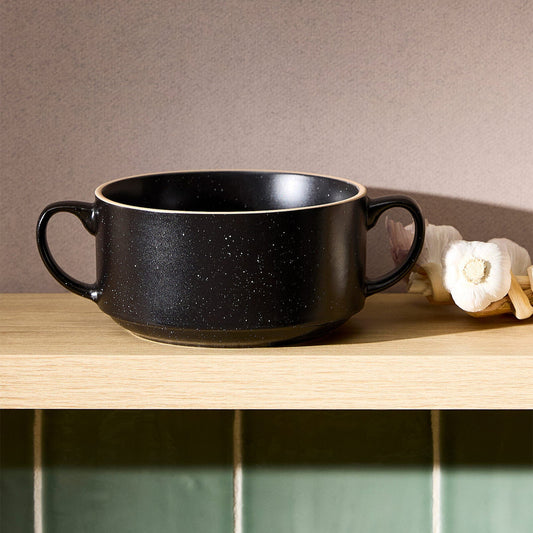 Black ceramic bowl on a wooden surface with a neutral background