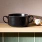 Black ceramic bowl on a wooden surface with a neutral background