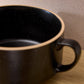 Black ceramic mug with speckled interior on a wooden surface