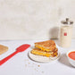 Grilled cheese sandwich on a plate with a Sourdough Storage Crock and a bowl of soup on a white surface.