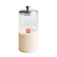 Clear Sourdough Storage Crock with a metal lid filled with a beige substance on a white background