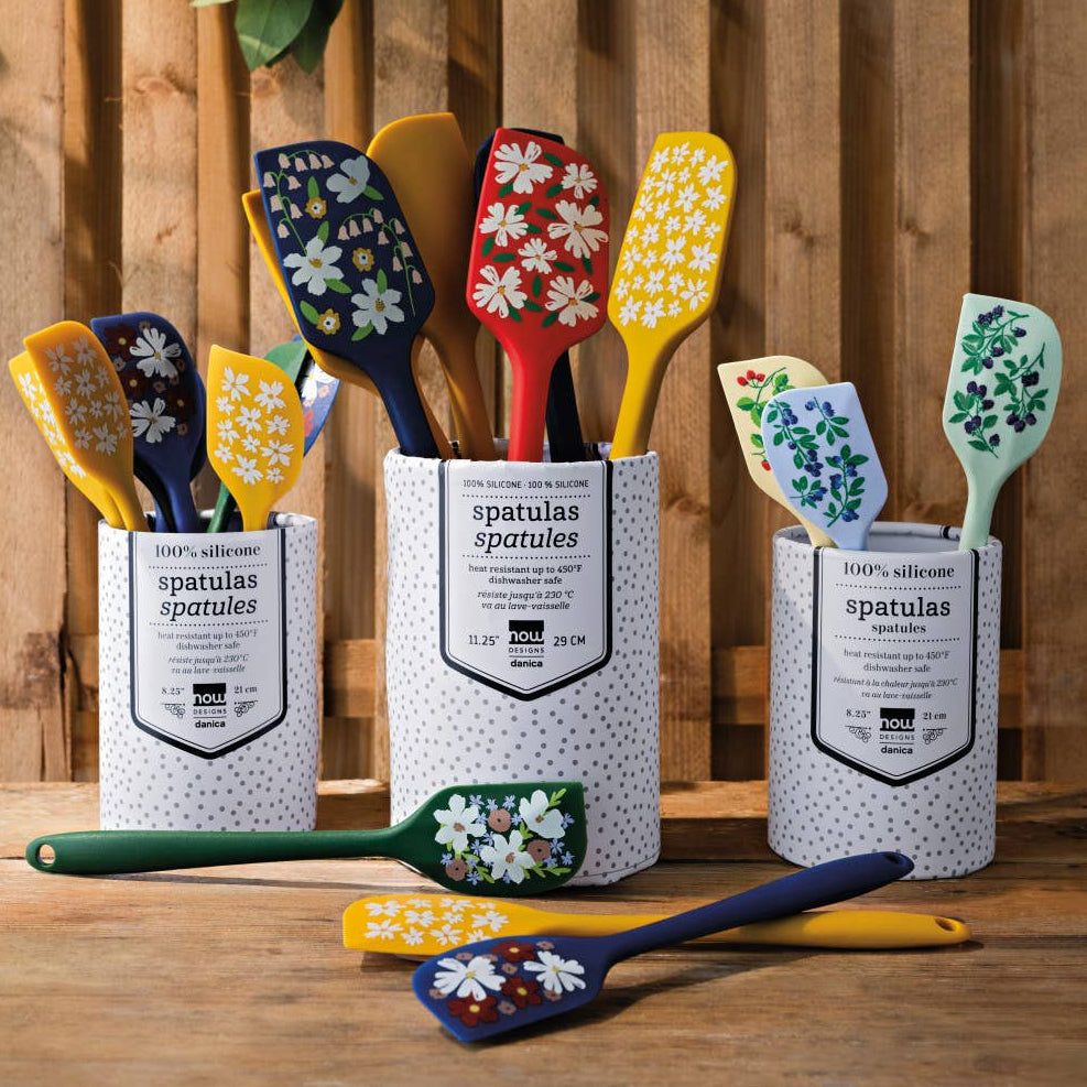 Set of colorful spatulas in a container against a wooden background